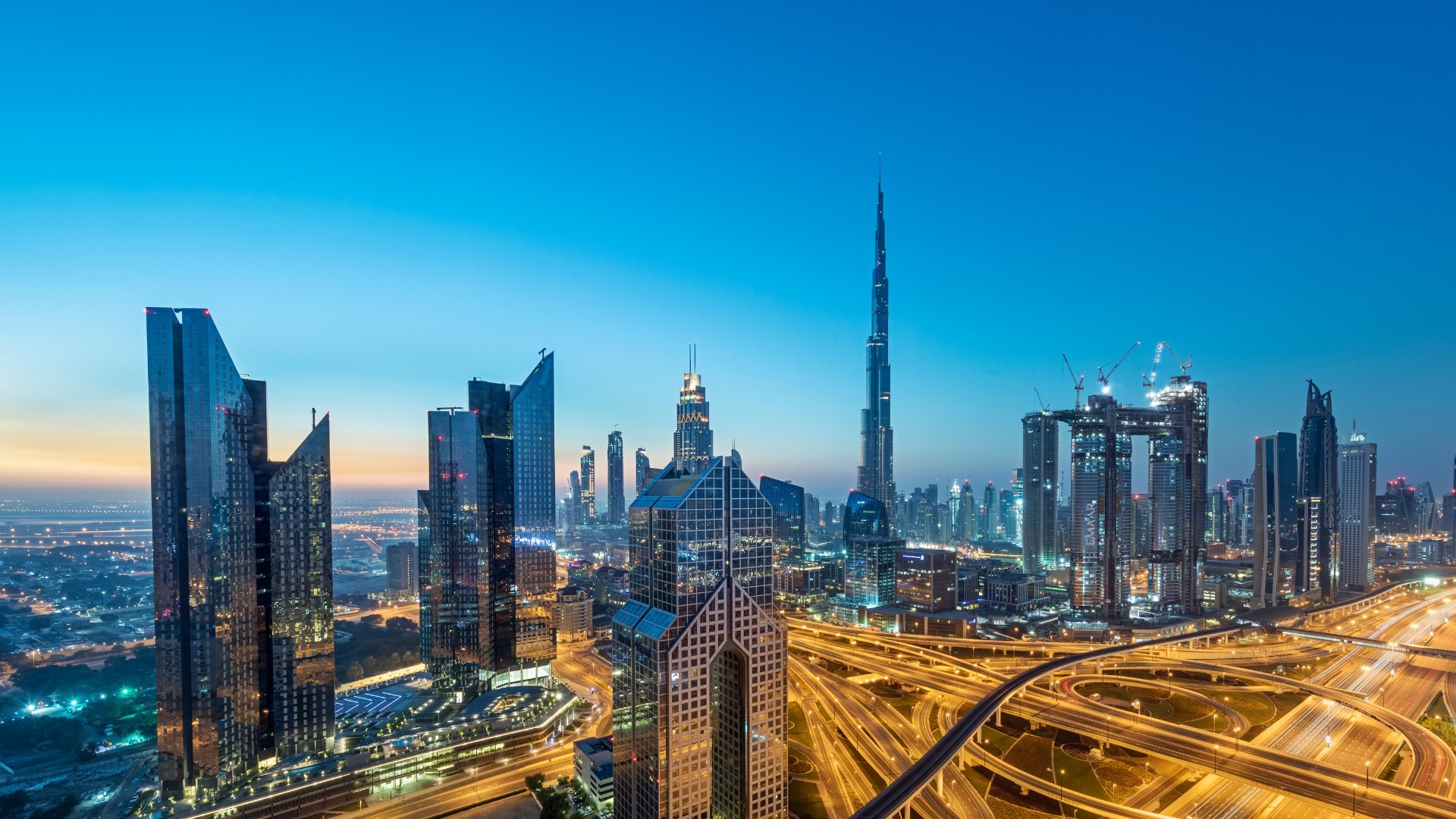 Dubai skyline at blue hour, with Burj Khalifa and illuminated highway interchanges